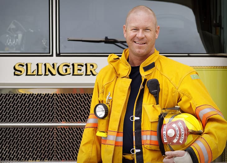 Tim, a Slinger firefighter standing next to a firetruck.