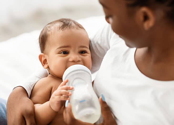 Another baby holding a bottle.